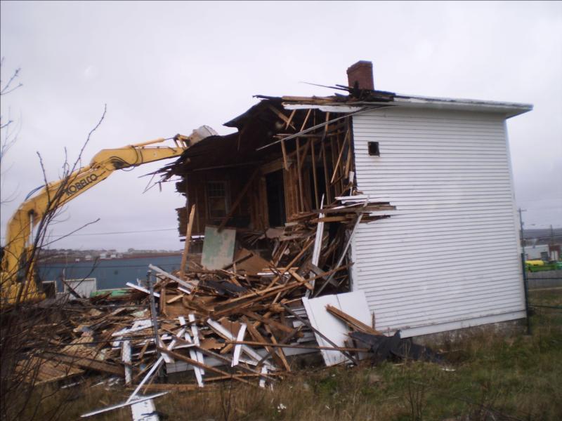 Building being demolished by a piece of heavy equipment