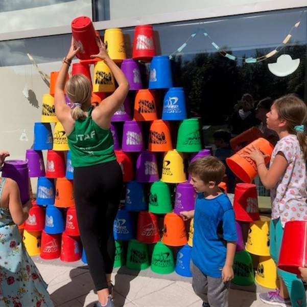 Daycamp staff and participants building a tower with colourful buckets