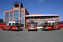 Three fire trucks are parked in front of a building.