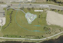 Arial photo of Quidi Vidi Park in St. John's showing green space in the middle where a pump track is to be installed, a dog park on the right and a parking lot on the left.