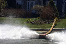 a firehose expelling water on a street from a hydrant