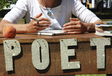 Poet sitting at a table with POET in front