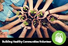 Hands holding plants; black background with text that reads Building Healthy Communities Volunteer