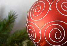 stock image of red christmas tree bulb with tree branches in the background