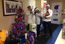 WestJet staff holding adoptable animals with gifts for them under the christmas tree