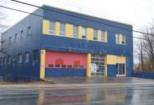 Image shows the former west end fire hall on Lemarchant Road, blue building with yellow trim and red garage door