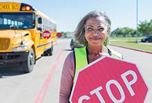 Crossing Guard holding a stop sign near a school bus