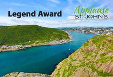 looking through the Narrows towards St. John's harbour. The green Southside hills are on the left and green-grey-gold rocks of Signal Hill on the right, the water and sky are blue with scattered clouds in the sky. Text at the top is Legend Award and a logo with text Applause in green and below it in black St. John's logo