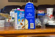 a cow milk and almond milk container are in the foreground; other recyclable containers are in the background.