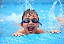 Image if a child in a swimming pool splashing water.