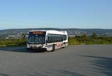 Image of a Metrobus in a parking lot with green trees in the background and blue sky