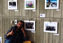Moammar with his photos at City Hall refugee photo exhibit