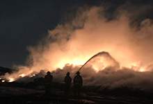 Silhouettes of three firefighters spraying a fire at the Robin Hood Bay Waste Management Facility landfill.