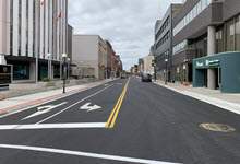 Image of Water Street showing new asphalt and buildings along the side of the street.