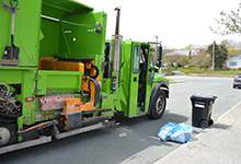 green city truck collects recycling at the curb