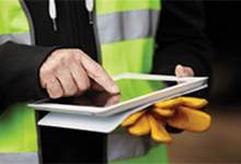 Worker with safety vest and gloves uses an iPad